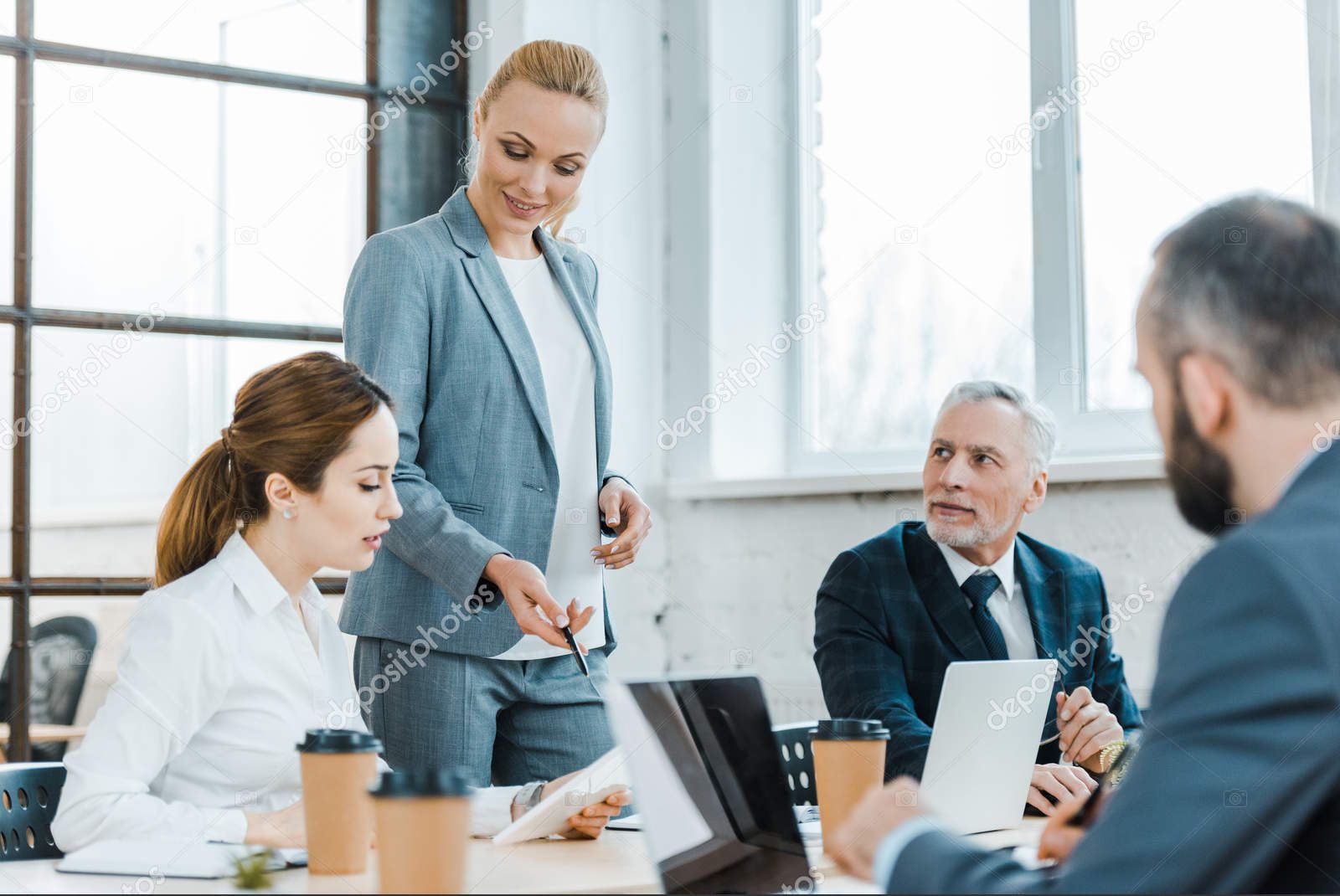 depositphotos_256807376-stock-photo-cheerful-business-coach-standing-coworkers